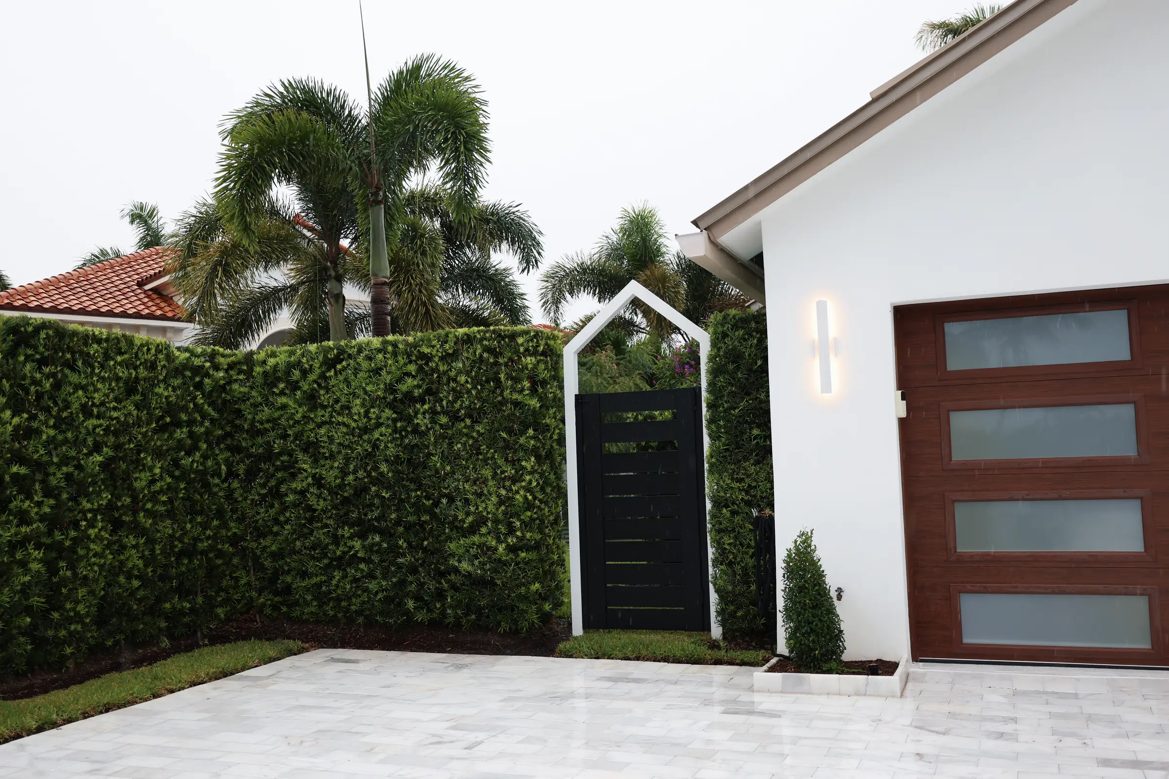 Black gate, clipped hedge, wood garage